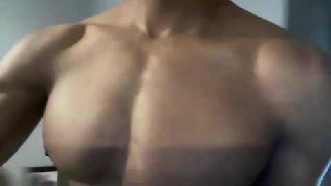 Media: Video of a light-skinned, muscular man's chest, showing defined pectoral muscles and nipples, with a blurred background of a bathroom setting.