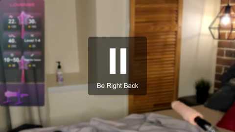 Media: A video of a modern bedroom with a wooden sliding door, a purple fitness tracker on a nightstand, a black and white digital clock, and a bed with grey sheets.