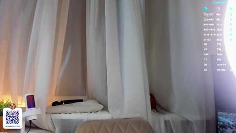 Media: Video of a minimalist bedroom with white sheer curtains, a beige quilted chair, and a white pillow on a white bed, with a QR code in the corner.