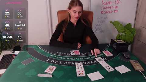 Media: Video of a young woman with light brown hair in a black top, sitting at a green felt casino table, surrounded by playing cards and chips.