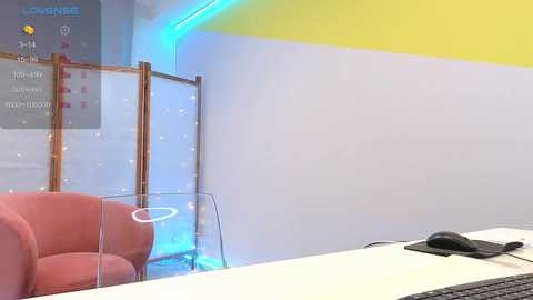 Media: Video of a modern, minimalist reception area with a white wall, blue accent lighting, a pink armchair, and a computer monitor on a desk.