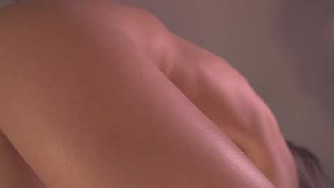 Media: Close-up video of a nude person's buttocks, with light skin tone, smooth texture, and slight muscle definition, viewed from the side. The background is out of focus, featuring muted colors.