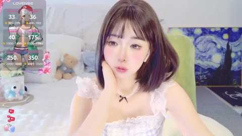 Media: Video of a young Asian woman with straight black hair, wearing a white lace dress, lying on a bed in a room with a Starry Night painting on the wall.