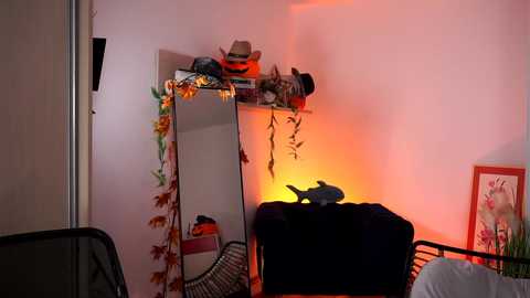 Media: Video of a cozy room with a large mirror, Halloween decorations, a chair, and a warm orange glow from a lamp, creating a festive, warm atmosphere.