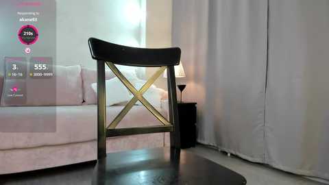 Media: Video of a modern living room featuring a black wooden chair with gold crossback, white sofa, and white curtains.