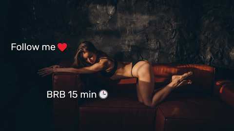 Media: Video of a fit, tan-skinned woman in black lingerie, posing seductively on a red leather couch, with dim lighting creating shadows, and the text \"Follow me \u2665\" and \"BRB 15 min\" in the corner.