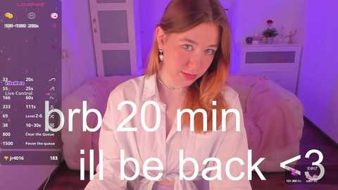 Media: Video of a young woman with long, light brown hair, wearing a white blouse, sitting on a pink couch. Text overlay reads \"I'll be back in 20 min.\