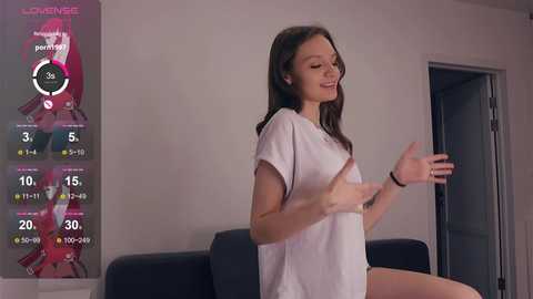 Media: Video of a young woman with long brown hair in a white t-shirt, exercising with virtual reality glasses in a modern, minimalistic room.