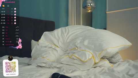 Media: Video of a messy bed with white sheets and yellow trim, set against teal walls with a spherical pendant light, and a TV screen showing social media icons.