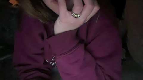 Media: A video of a person wearing a maroon jacket with a gold ring on their finger, with a dark background suggesting an indoor setting.