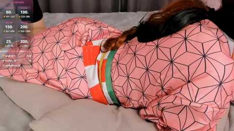 Media: Video of a person lying on a bed with a pink geometric-patterned dress, showcasing a digital health tracking screen overlaying the image.