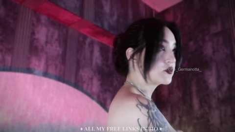 Media: A video of a pale-skinned, black-haired woman with dark makeup, wearing a black dress, standing against a textured, purple wall with a red accent. Text overlay reads \"All My Favourite Links 2.0.\