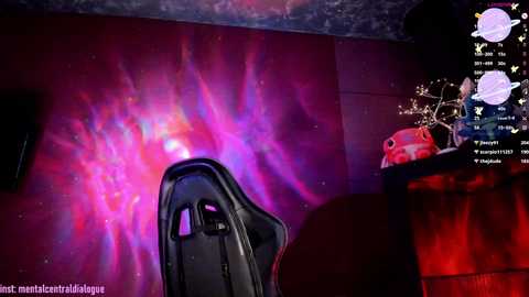 Media: A vibrant video of a gamer's setup: a black gaming chair, a red desk, and a mesmerizing neon purple and pink galaxy-themed LED backdrop.