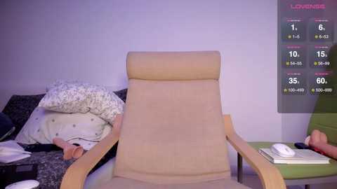 Media: Video of a beige recliner chair in a minimalist room with a white wall, a green side table, and a digital health monitor displaying heart rate and sleep data.