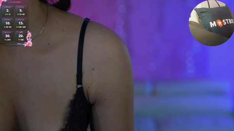 Media: Video of a woman's bare upper back and shoulder in a black lace bra, with a smartphone displaying a \"N\" icon and a purple and blue background.