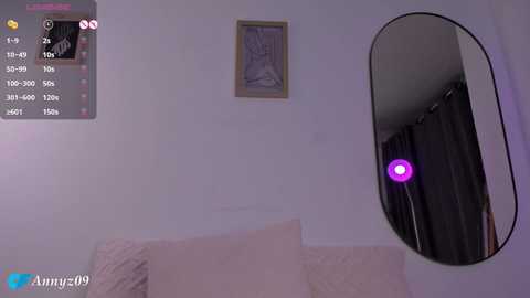 Media: A video of a bedroom with a large oval mirror on the wall, showing a person wearing a black outfit. The room has a soft purple light and a framed picture.