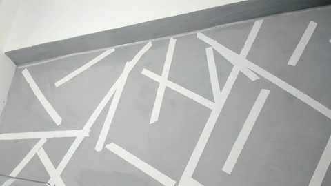 Media: Video of a modern, geometrically patterned, gray-tiled floor featuring white, angular lines forming a complex, abstract design. The background is plain white, emphasizing the tiled area's intricate, minimalist style.