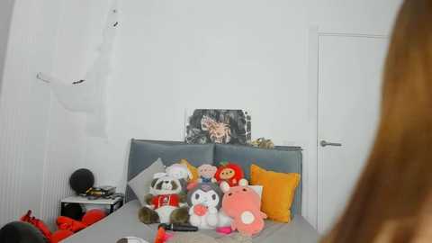 Media: Video of a messy bedroom with plush toys, a stuffed animal head on a bed, and a white door in the background.