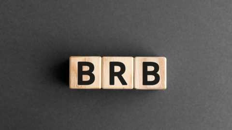 Media: A video of three wooden letter tiles arranged vertically, spelling \"BRB\" on a dark gray textured background. The letters are bold and black, contrasting with the light beige wood.