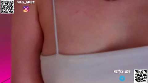 Media: Video of a close-up of a woman's bare shoulder and upper chest, showing a light pink hue and a small, faint scar. She wears a white spaghetti-strap tank top. QR codes and social media icons are in the top-left corner.