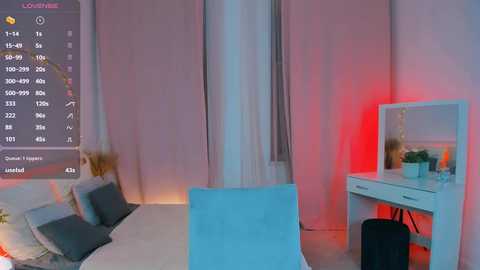 Media: Video of a modern bedroom with pastel pink walls, a white vanity table with a mirror, and a blue chair. Soft lighting and a digital display showing time and weather are visible.