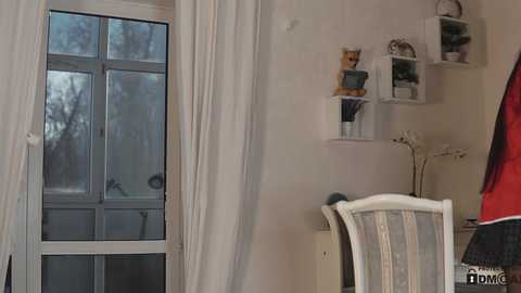 Media: A video of a cozy room with a white-framed window, sheer curtains, white shelves holding teddy bears, a striped chair, and a desk lamp.