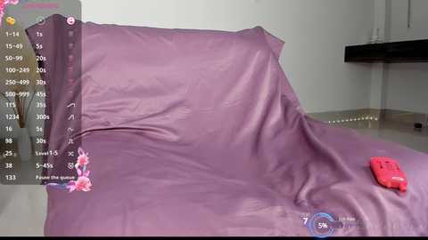 Media: A video of a purple bedspread with a red pillow and a red shoe on a beige floor, in a modern, minimalist bedroom.