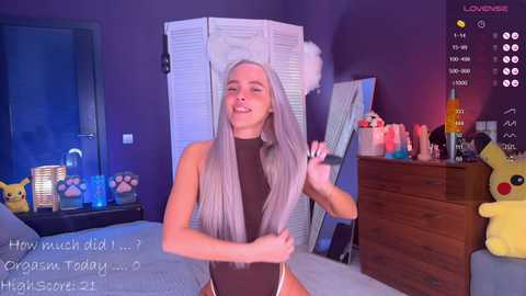 Media: A video of a young, slender woman with long, straight platinum blonde hair, wearing a black leotard, standing in a colorful, cluttered bedroom with Pok\u00e9mon-themed decor.