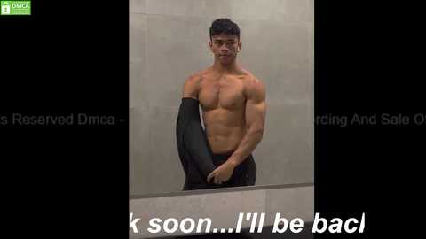 Media: Video of a shirtless, muscular Asian man with short dark hair, standing in a modern bathroom with gray tiles. He holds black pants, looking contemplative. Text: \"I'll be back.\