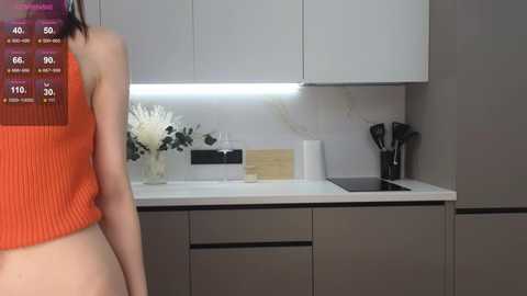 Media: Video of a modern kitchen with white cabinets, an orange tank top, and a digital health tracking app interface overlaid.