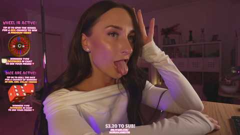 Media: Video of a young woman with long dark hair, wearing a white off-shoulder sweater, licking her fingers, in a dimly lit room with a purple glow, surrounded by gaming elements and text overlays.