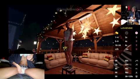 Media: Video of a VR scene featuring a woman in a grey top and jeans standing on a stool in a starlit patio with a beige couch, wooden beams, and a city skyline background.