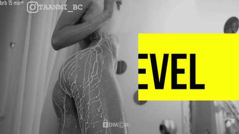 Media: Black-and-white video of a nude woman showering, water cascading over her body, emphasizing her curves. Yellow \"EVEL\" logo in the background, with social media icons.