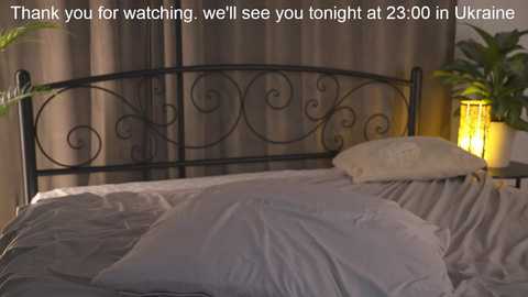 Media: Video of a neatly made bed with a black wrought-iron headboard, beige curtains, and a yellow lamp on the nightstand. Text overlay: \"Thank you for watching, well see you tonight at 29.00 Ukrainian time.\