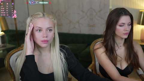 Media: Video of two young women, one blonde with long hair, the other brunette, sitting on green chairs in a dimly lit room.