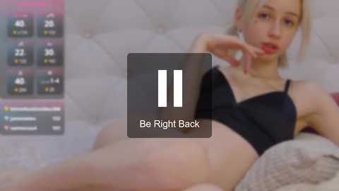 Media: A video of a blonde woman in black lingerie reclining on a tufted bed, with a digital display showing a \"Be Right Back\" message overlay.