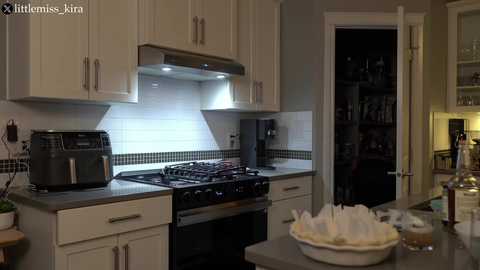 Media: Video of a modern kitchen with white cabinets, stainless steel appliances, a gas stove, tiled backsplash, and a bowl of white napkins on a gray countertop.