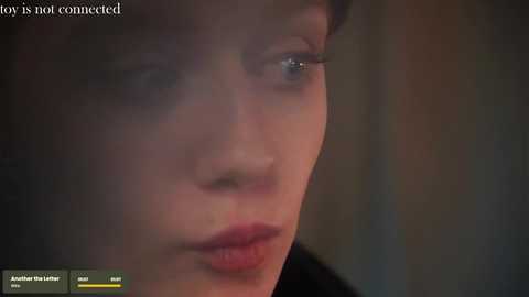 Media: A close-up video of a young woman with fair skin and short, dark hair, eyes partially obscured by shadows, wearing makeup, with a blurred, dim background. Text at the top reads, \"View is not connected.\