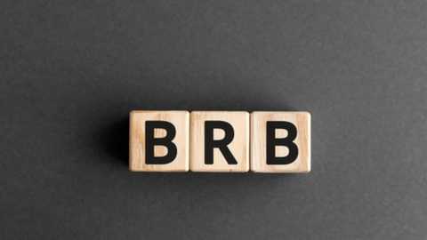 Media: Video of a wooden letter block puzzle spelling \"BRB\" in black letters on a dark gray, textured surface. The blocks are arranged horizontally.