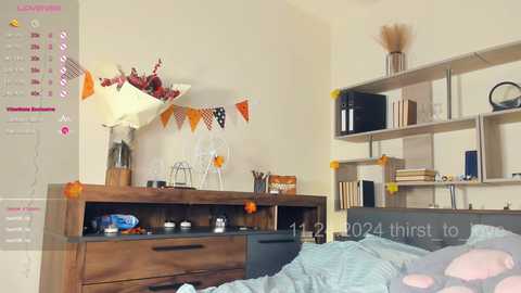 Media: Video of a minimalist bedroom with beige walls, wooden dresser, white bed, and shelves adorned with books, decor, and a calendar.