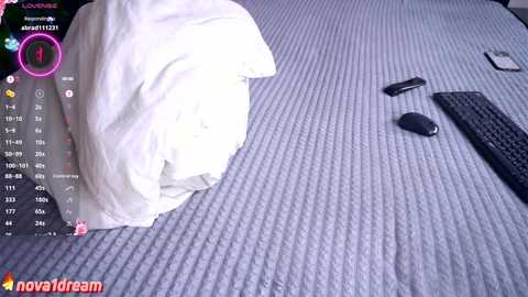 Media: Video of a messy bed with a crumpled white duvet, a black mouse, and a keyboard on a textured gray sheet, with a live streaming overlay in the top left.