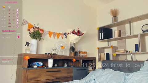 Media: Video of a cozy, minimalist bedroom with a wooden dresser, flowers, a calendar, and a \"24th first to love\" chalkboard sign on a shelf.