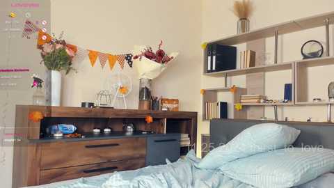 Media: Video of a cozy, organized bedroom with a wooden dresser, bookshelf, light blue bedding, and colorful decorations; modern, minimalist style.