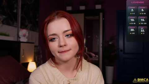 Media: A video of a young woman with fair skin and red hair, wearing a cream-colored top, in a dimly lit room with a digital clock showing 2:15 AM.