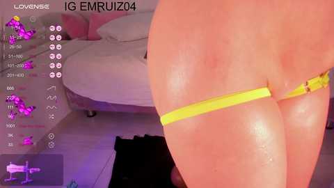 Media: A video of a close-up of a woman's lower back and buttocks, with a yellow thong partially pulled down, showing wet skin. The background features a pink couch.