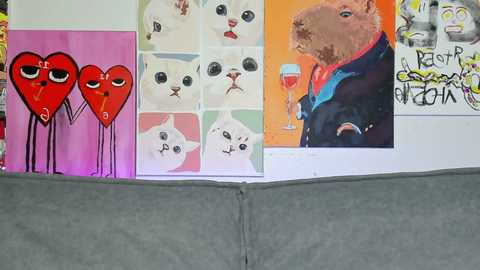 Media: A video of a colorful, eclectic wall featuring four paintings: a red heart with two eyes, a white cat with red eyes, a bear in a blue suit holding a glass, and a pink heart with eyes.