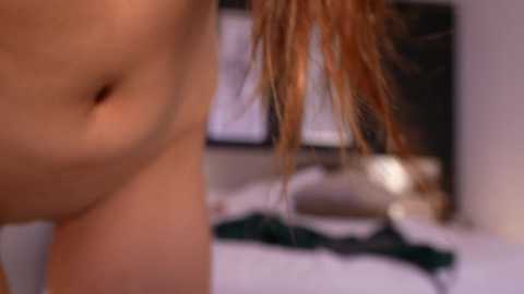 Media: A close-up video of a woman's navel with auburn hair, blurred background showing a bed with green fabric.