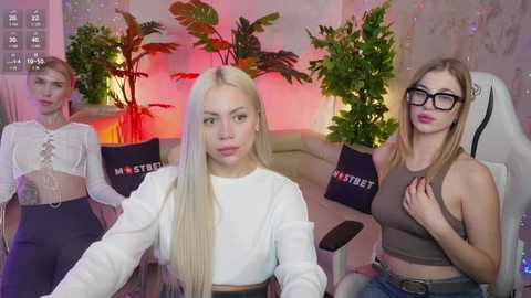 Media: Video of three young women in casual, revealing outfits; blonde, brunette, and redhead, sitting on a couch with green plants in background, holding \"Mystery Street\" bags.