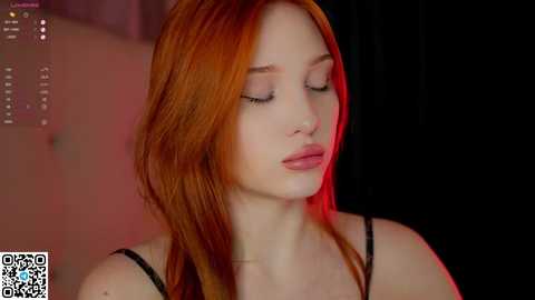 Media: Video of a pale-skinned, red-haired woman with closed eyes, wearing black lingerie, against a dark background, with a QR code in the bottom left corner.