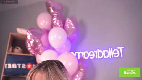 Media: A video of a woman with blonde hair, holding a bunch of pink and silver balloons, against a gray wall with the \"Tennessee\" logo.